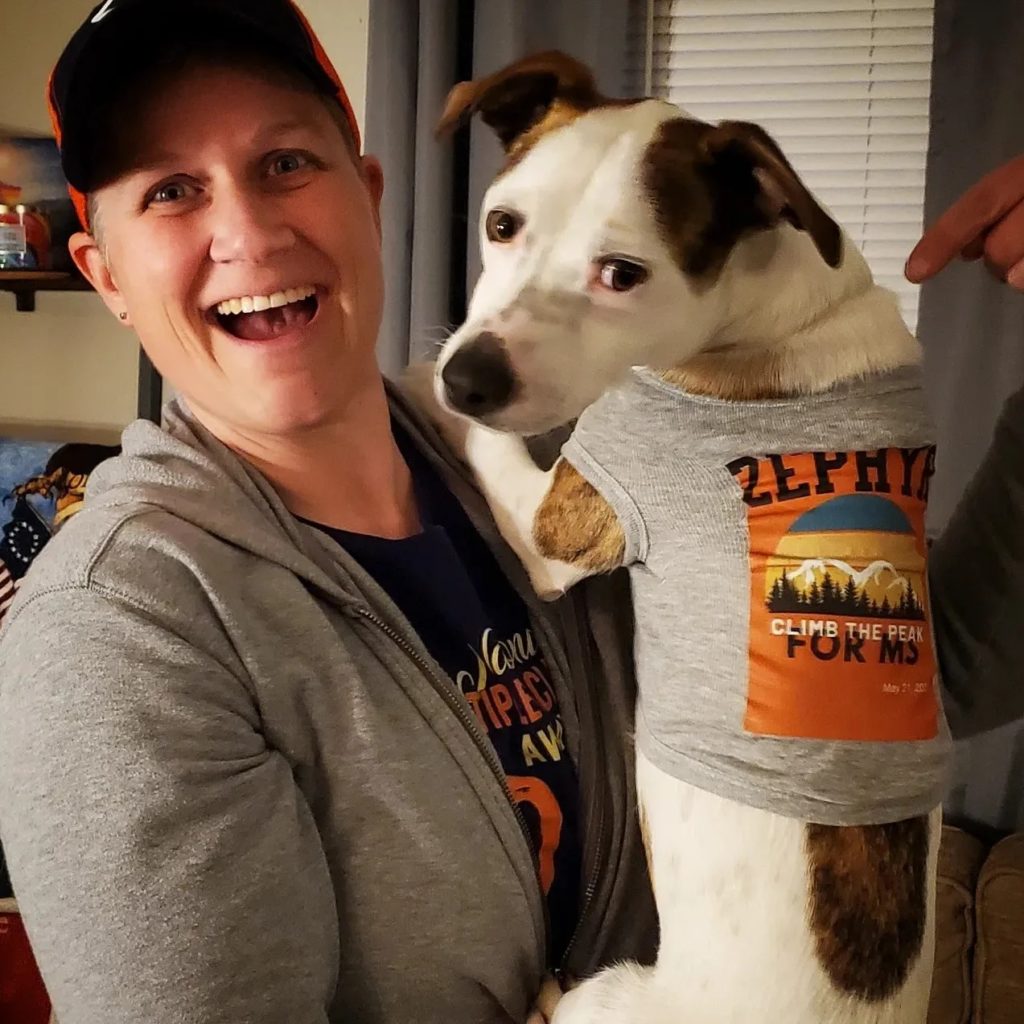 Sarah J. Locke holds up her dog with an MS awareness shirt on